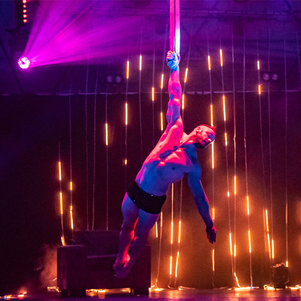 An artist suspended in the air while led light shimmers and rains down