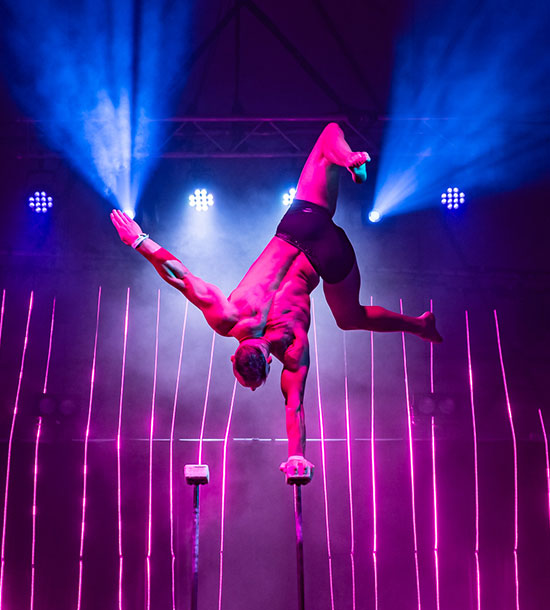 a man silhouetted in a rich array of lighting, while performing a handstand 